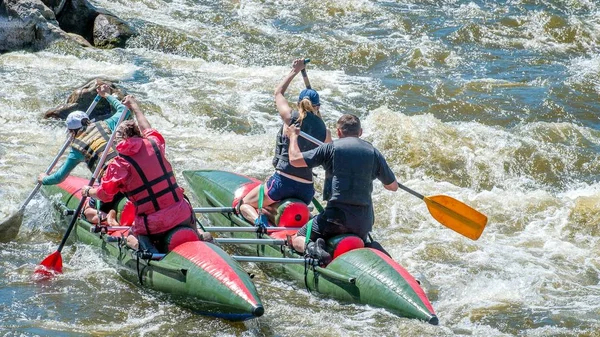 Rafting, kayaking. Athletes in sports equipment are sailing on a rubber inflatable boat in a boiling water stream. Teamwork. Water splashes close-up. Extreme sport.