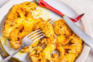 Pişmiş karnabahar bifteği, kırmızı biberli bir tabağa baharat serpiştirilmiş, üst manzara, yakın çekim.