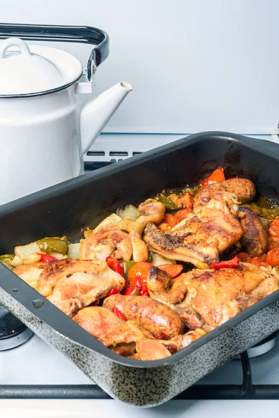 Home cooked chicken scarpariello in a baking sheet on a gas stove - chicken with sausages and vegetables, Italian-American dish
