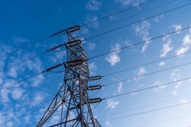 Yüksek voltajlı elektrik hattının yüksek kuleleri mavi gökyüzüne karşı, alt manzara