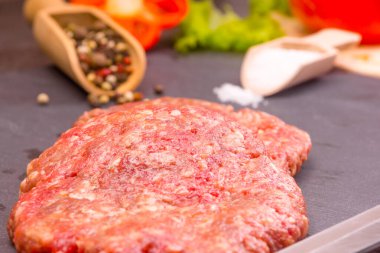 Mutfak arka planı, karanlık bir arka planda tuzlu, biberli ve kesilmiş sebzeli hamburgerler.