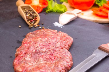 Mutfak arka planı, karanlık bir arka planda tuzlu, biberli ve kesilmiş sebzeli hamburgerler.