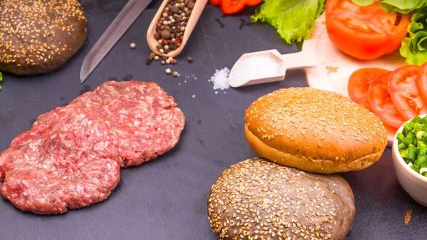 Mutfak arka planı, çiğ köfteler ve hamburgerler, tuz, biber ve doğranmış sebzeler.