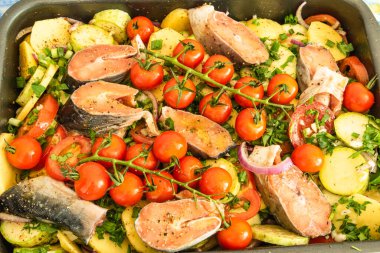Alabalık ve sebzeli rosto pişirmek için doğranmış çiğ sebze ve balık parçaları.