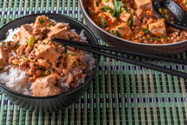 Popüler bir Çin Sichuan çanak baharatlı Mapo tofu ile pirinç bir kase ve bir bambu peçete Mapo soya peyniri bir plaka