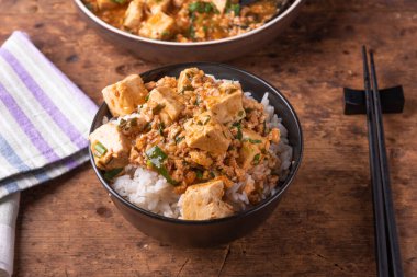 Popüler Çin Sichuan çanak-baharatlı Mapo tofu ve rustik ahşap masada Mapo soya peyniri bir plaka ile pirinç bir kase