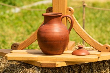 Güneşli bir günde ahşap bir stand üzerinde bir kapak ile kil sürahi