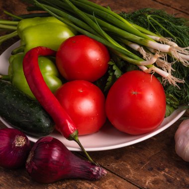 Taze sebzeler, domatesler, kiraz domatesleri, yeşil biberler, biberler, soğanlar, salatalıklar, sarımsak ve otlar kırsal ahşap bir masa üzerinde - kırsal tarz, sağlıklı, organik gıda konsepti