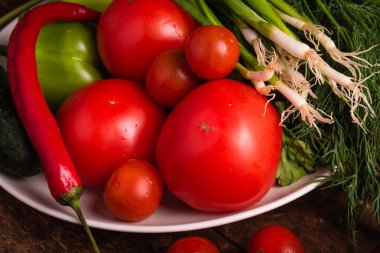 Taze sebzeler, domatesler, kiraz domatesleri, yeşil biberler, biberler, soğanlar, salatalıklar, sarımsak ve otlar kırsal ahşap bir masa üzerinde - kırsal tarz, sağlıklı, organik gıda konsepti