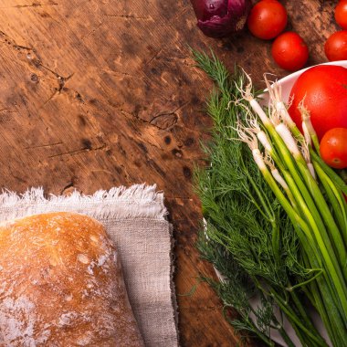 Taze sebzeler, domatesler, soğanlar, salatalıklar, sarımsak ve otlar üzerinde ve ciabatta ekmeği ahşap bir masada - İtalyan kırsal tarzı, mutfak arka planı, kopyalama alanı