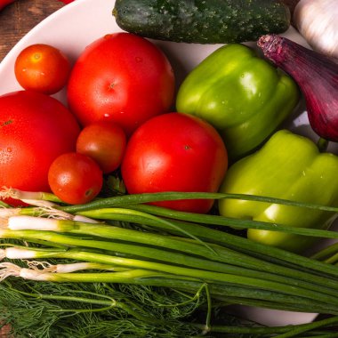 Taze sebzeler, domatesler, kiraz domatesleri, yeşil biberler, biberler, soğanlar, salatalıklar, sarımsak ve otlar kırsal ahşap bir masa üzerinde - kırsal tarz, sağlıklı, organik gıda konsepti