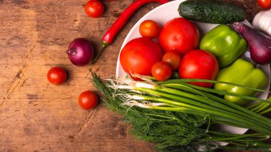 Taze sebze domatesleri, kiraz domatesleri, yeşil biber, kırmızı biber, soğan, salatalık, sarımsak ve otlar kırsal ahşap bir masa üzerinde - mutfak arka planı, fotokopi alanı, kırsal tarz, sağlıklı yeme konsepti