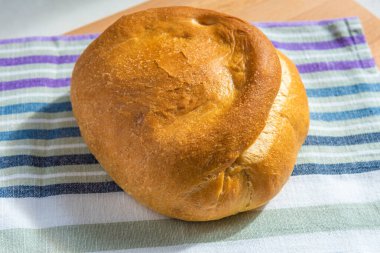 Bir somun ev yapımı buğday ekmeği kırsal bir mutfak havlusunda, üst manzara, doğal ışık.