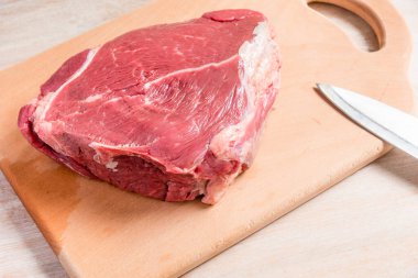 Ahşap bir tahtanın üzerinde büyük bir parça çiğ et.