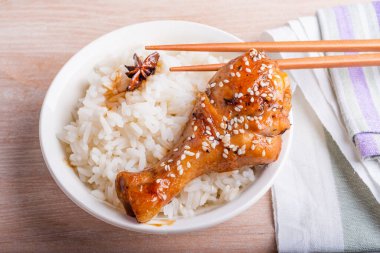 Bir kase pilav ve tavuk budu yapışkan tatlı bir sosta kızartılmış susam tohumları, çubuklar ve Asya mutfağı serpiştirilmiş..