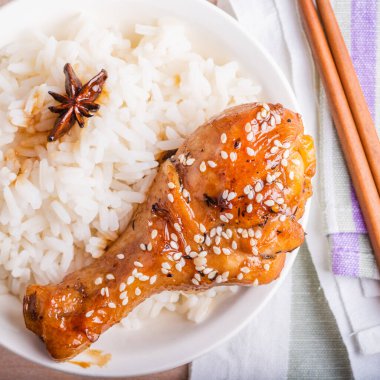 Bir kase pilav ve tavuk budu yapışkan tatlı bir sosta kızartılmış, susamlı, yakın plan Asya mutfağı serpiştirilmiş.