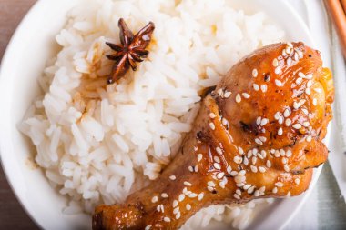 Bir kase pilav ve tavuk budu yapışkan tatlı bir sosta kızartılmış, susamlı, yakın plan Asya mutfağı serpiştirilmiş.