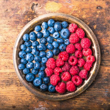 Lezzetli olgun böğürtlen ve ahududu sembolü olarak yin ve yang 'ı taşralı ahşap bir tabakta yakın plan, üst manzara