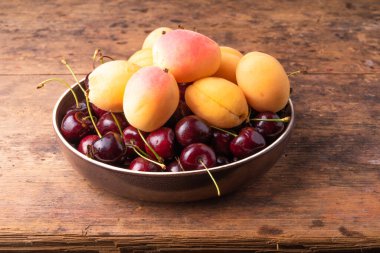 Lezzetli kayısı ve kiraz üzümleri yakın plan ahşap bir masada bir tabakta.