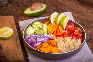 Kinoalı salata kasesi; havuç; avokado; soğan; biber; limon dilimli domates - vejetaryen yemeği; Buda kasesi