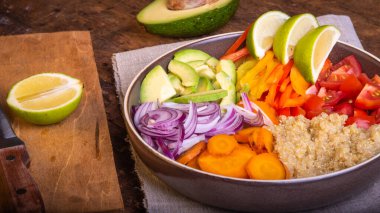 Kinoalı salata kasesi; havuç; avokado; soğan; biber; limon dilimli domates - vejetaryen yemeği; Buda kasesi