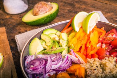 Kinoalı salata kasesi; havuç; avokado; soğan; biber; limon dilimli domates - vejetaryen yemeği; Buda kasesi