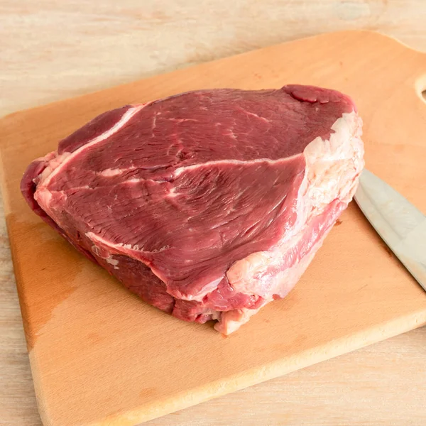 Ahşap bir tahtanın üzerinde büyük bir parça çiğ et.