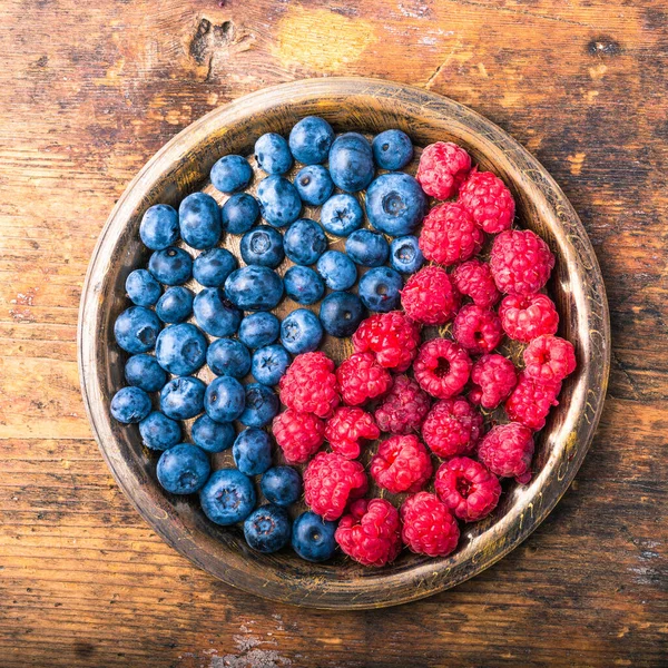 Lezzetli olgun böğürtlen ve ahududu sembolü olarak yin ve yang 'ı taşralı ahşap bir tabakta yakın plan, üst manzara