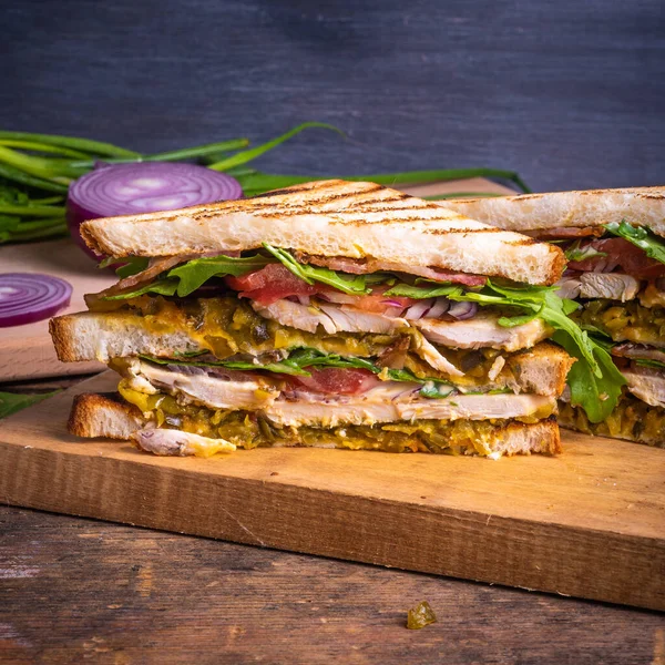 美味的三明治被切成三角形 烤面包配鸡胸肉 炸咸肉 芥末泡菜和绿豆片 背景深色 复制空间 — 图库照片