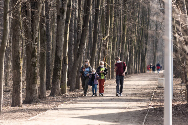 Moscow, Russia, March 28, 2020 - A family walks in a park wearing masks protecting from covid-19. The beginning of the coronavirus epidemic in Moscow.