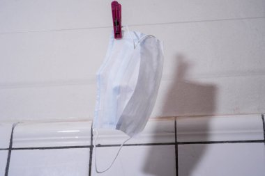 Fırlatılabilir tıbbi maske banyoda kurutuldu. Coronavirus covid-19 'a karşı koruyucu madde eksikliği kavramı.