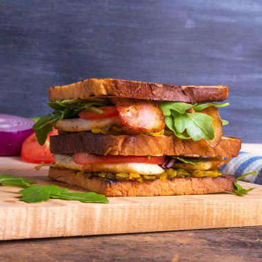 Tavuk göğsü, pastırma, salata ve sebzeli büyük lezzetli ev yapımı kare sandviç.