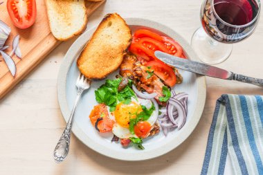 Köy kahvaltısı. Domuz pastırmalı, soğanlı ve domatesli yumurta. Hafif ahşap arka planda tost.