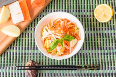 Japon aperatifi - Elmalı turp salatası ve bir kasede havuç ve bambu peçetesinde çubuklar.