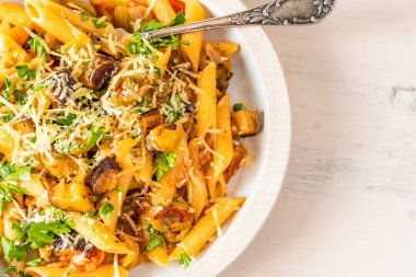 Açık bir kırsal masada tabak üzerinde makarna caponata. Tarif kopyalama alanı