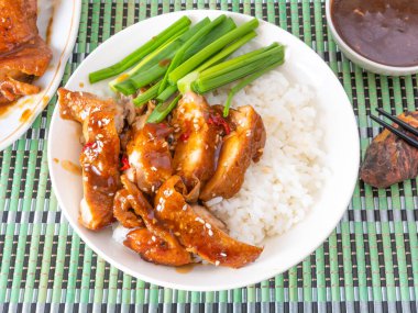Teriyaki tavuklu bir kase pilav, yemek çubukları, bambu peçetesinde sos, üst manzara. Asya mutfağı - Japon, Çinli, Koreli.