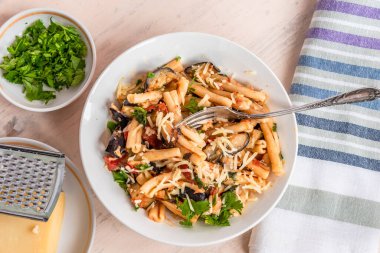 Patlıcanlı vejetaryen İtalyan makarnası, üst manzara, açık kırsal bir masada peçeteli makarna.