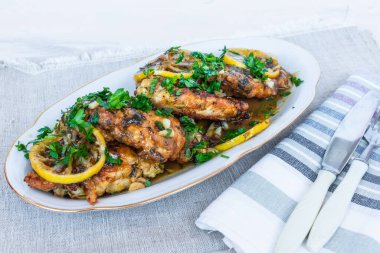 Tavuk Francese, İtalyan-Amerikan yemeği. Beyaz tabakta limon dilimleri soslu kızarmış tavuk göğsü..