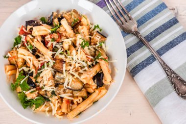 Patlıcanlı vejetaryen İtalyan makarnası, üst manzara, açık kırsal bir masada peçeteli makarna.