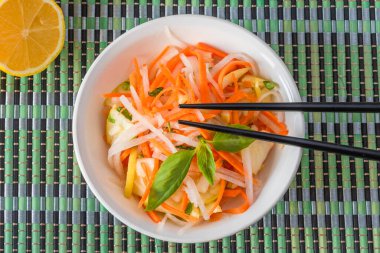 Japon aperatifi - Elmalı turp salatası ve bir kasede havuç ve bambu peçetesinde çubuklar.