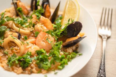 Açık ahşap bir tabakta deniz mahsullü risotto, yakın plan İtalyan mutfağı.