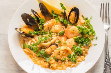 Açık ahşap bir tabakta deniz mahsullü risotto, yakın plan İtalyan mutfağı.