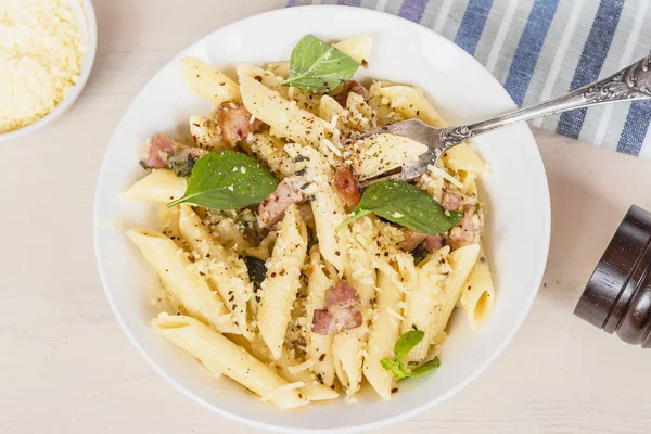 Geleneksel İtalyan mutfağı yemeği. Pancetta 'lı makarna, parmesan peyniri ve fesleğen, yakın plan, üst manzara.