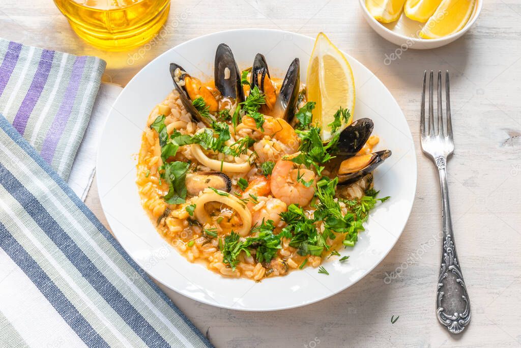 Seafood risotto in a plate on a light wooden background - italian cuisine