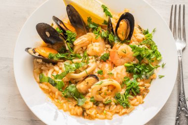 Açık ahşap bir tabakta deniz mahsullü risotto, yakın plan İtalyan mutfağı.