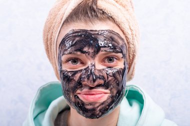 Nemlendirici ve temizleyici siyah maskesiyle genç ve çekici bir kadının portresi.