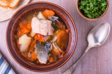 Somon çorbası. Kil tabakta patates, havuç ve domates ile kalın balık çorbası. Üst görünüm.