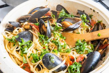 Ev yapımı midyeli makarna, büyük bir tavada maydanoz ve fesleğen serpiştirme. Kabuklu linguine ve sebze sosu.