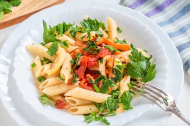 Traditional Italian pasta with peppers and tomatoes and parsley in a bowl close-up, penne clipart