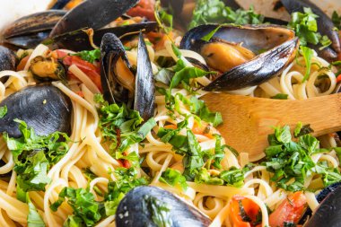 Ev yapımı midyeli makarna, büyük bir tavada maydanoz ve fesleğen serpiştirme. Kabuklu linguine ve sebze sosu.